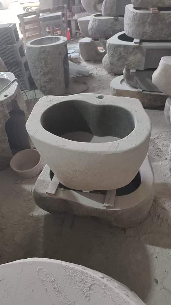 Round natural stone pedestal wash basin photographed in the workshop