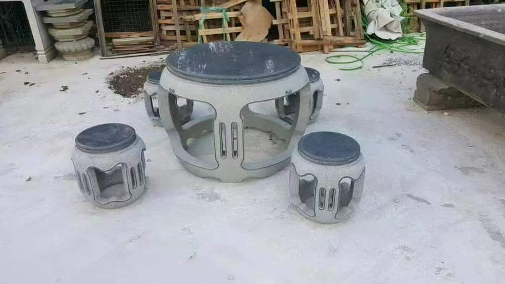 Round natural stone table with matching cylindrical stools in the workshop