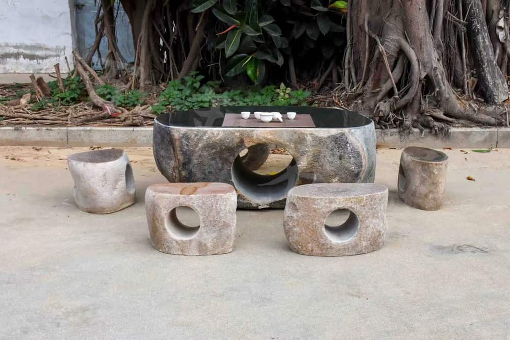 Group of custom natural stone basins displayed in front of a large tree