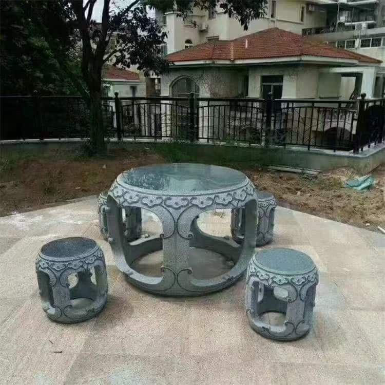 Round outdoor stone table with four matching stone stools in a courtyard