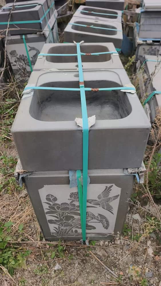 Multiple rectangular stone basin components secured for workshop handling